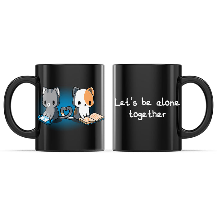 Ceramic Mug_TeeTurtle Let's Be Alone Together black mug featuring a cat playing video games, and a cat reading a book with their tails forming a heart between them.